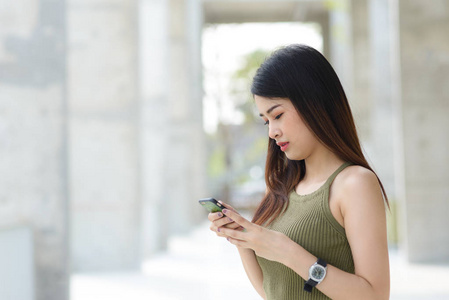 年轻的亚洲女子与智能手机站在街头 blurre