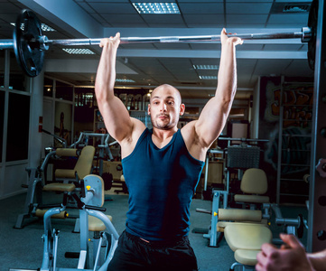 肌肉男子做练习与杠铃在健身房