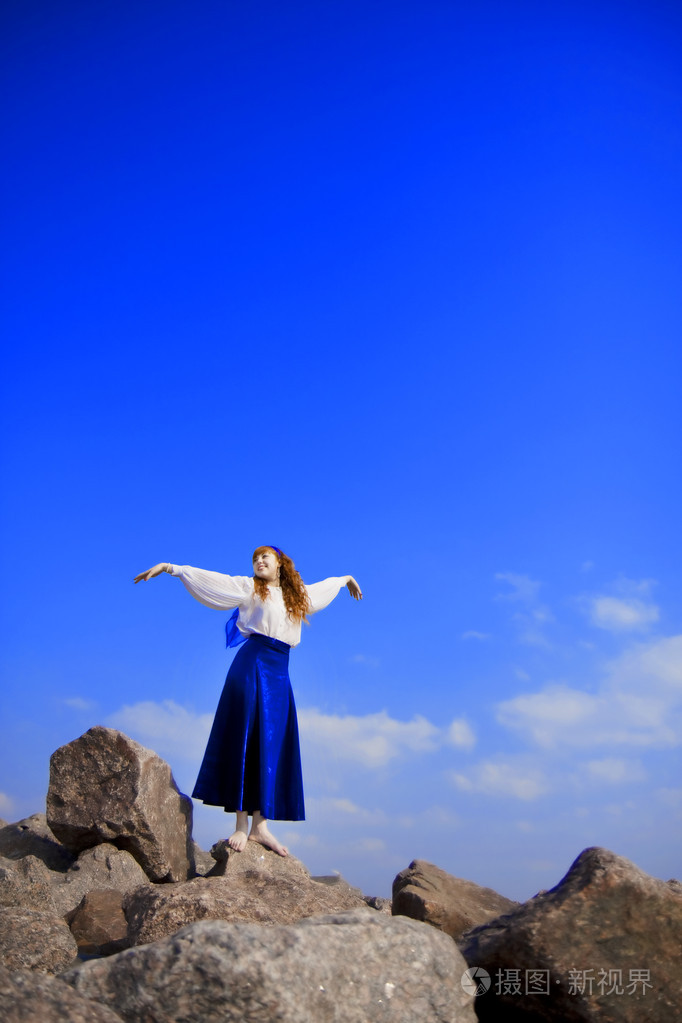 穿着蓝色裙子的女孩模特在蓝天背景下