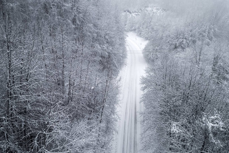 在希腊北部的 地区, 有一条道路的白雪皑皑的森林鸟瞰图。从上面捕获的无人驾驶飞机