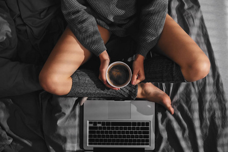 女孩在床上喝咖啡和使用笔记本电脑的鸟瞰图