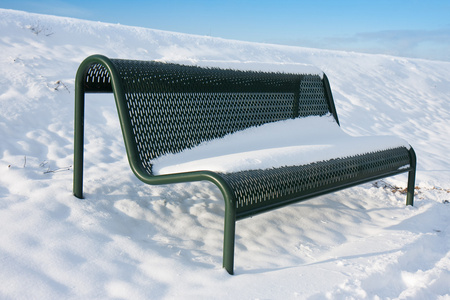 在冬季被雪覆盖的绿色铁板凳图片