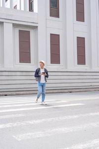 年轻的亚裔男子在帽子行走使用智能手机拍照城市