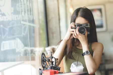 愉快的亚洲妇女藏品古董照相机在咖啡馆