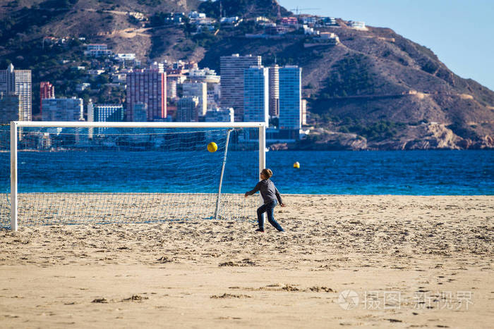 在沙滩上踢足球的男孩