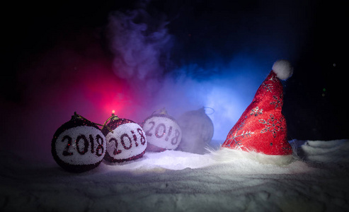 红色圣诞节球与2018数字和圣诞老人条款帽子在自然雪背景。新年快乐2018概念。复制空间。选择性焦点