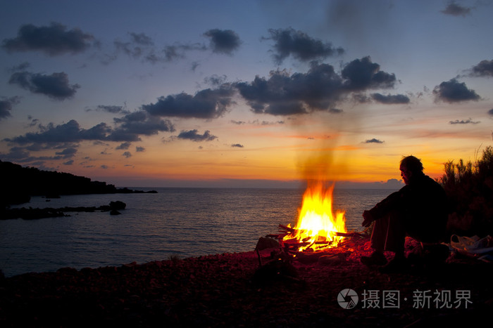 男子坐在炉火旁