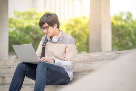 亚洲年轻男子大学学生坐在楼梯上