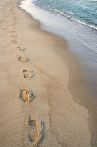 脚在波到达距旁边的印记。浪漫的散步