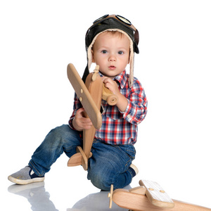 一个小男孩在飞行员帽，手里的木制飞机