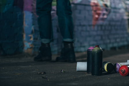 街头画家的低断面涂鸦在晚上, 罐与气溶胶油漆前景