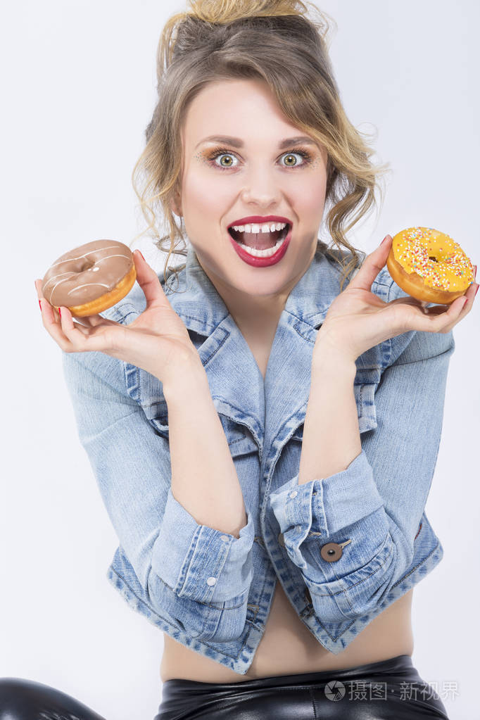惊讶的白种金发女孩吃两个大甜甜圈在手