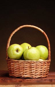 多汁的青苹果在棕色背景上的木桌上的篮子里
