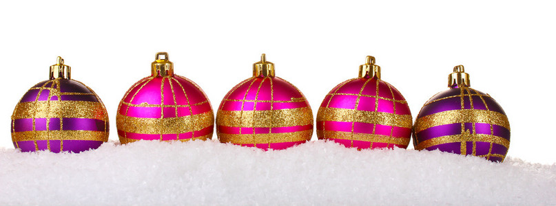 在雪上白色隔离美丽粉色和紫色圣诞球