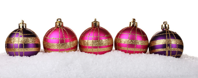 在雪上白色隔离美丽粉色和紫色圣诞球