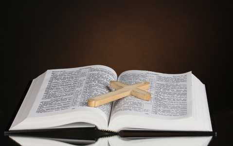 俄罗斯开放的神圣的圣经与木制十字架上棕色背景照片