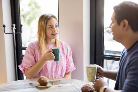 年轻漂亮的金发女郎喝咖啡, 和她的男朋友在一家餐馆聊天