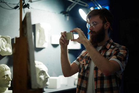当代大胡子画家的肖像完成他的绘画和拍摄的杰作与智能手机