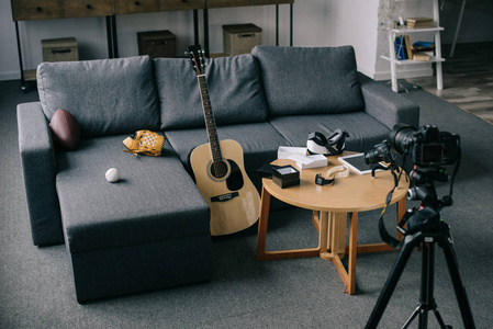 带灰色沙发的声学吉他和照相机在空房间