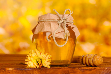 罐蜂蜜和表在黄色背景上的木制 drizzler