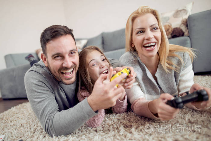 嬉戏的家庭一起玩电子游戏在客厅里
