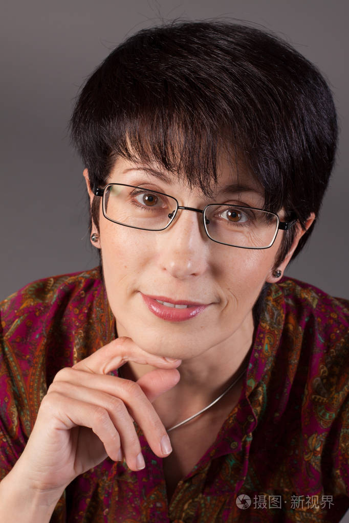 一个微笑优雅的中年白种女人的肖像反对灰色背景