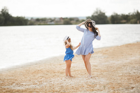 带条纹帽子的母亲在沙滩上漫步