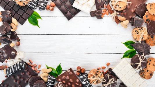 各式巧克力配坚果饼干和可可粉。在白色的木质背景。顶部视图。复制文本空间