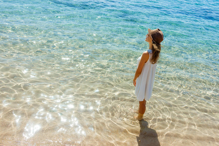 快乐的女人在夏天白色礼服在海滩上。女孩放松和享受和平在假期