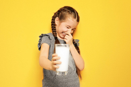 乳品过敏的小女孩在彩色背景上持有牛奶玻璃