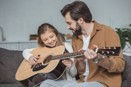 快乐的父亲教女儿演奏声学吉他