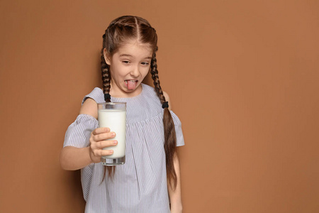 乳品过敏的小女孩在彩色背景上持有牛奶玻璃