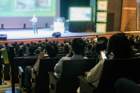 观众的后观在会议厅或研讨会的舞台上聆听演讲者在低光情况下, 商业和