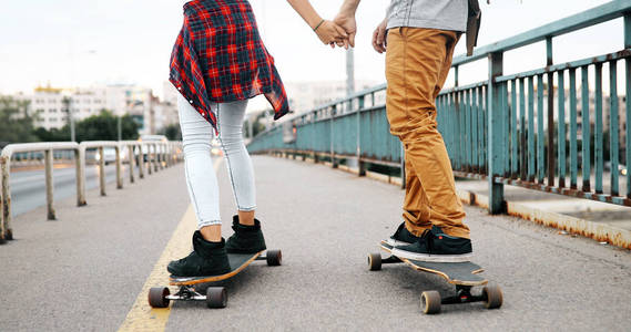 有吸引力的年轻夫妇骑滑板和让大家一起开心