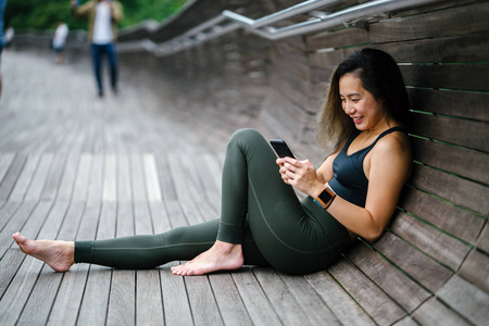 一个迷人的, 年轻的中国亚裔女子的肖像, 穿着运动, 积极佩戴手机