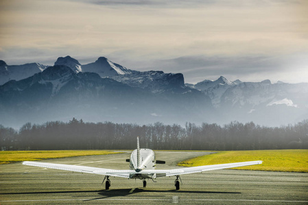 螺旋桨飞机在机场停车。在高山前面的小飞机场。日落结束山脉