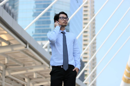 自信的年轻的亚洲商人在城市建筑城市背景电话通话