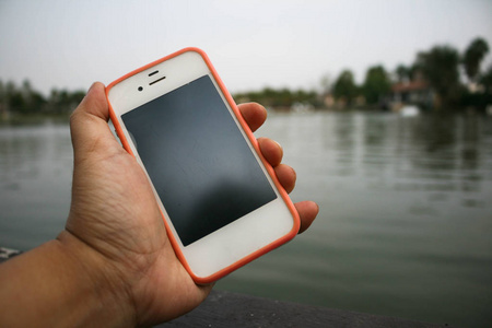 人手手持手机在湖边