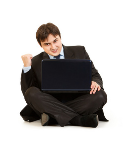 兴奋的现代商人，坐在地板上有笔记本电脑和欣喜他 s
