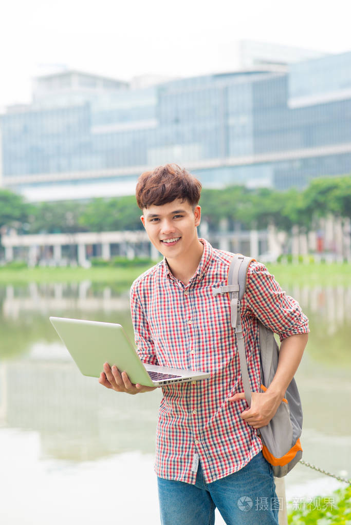 有吸引力的男亚裔学生在校园里使用笔记本电脑照片-正版商用图片03w