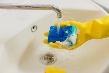 用黄色橡胶手套清洁浴室水龙头用蓝色海绵家务, 春季清洁概念