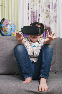 男孩正在看视频与虚拟现实眼镜, 室内。数字虚拟现实设备