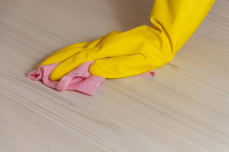 女式手在黄色手套清洁轻木现代桌用粉红色布料为家庭维护和管家