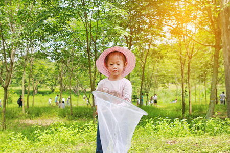 可爱的小亚洲女孩夏天在昆虫网地里戴草帽