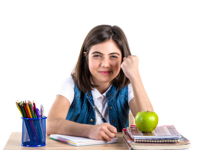 一个美丽的学校女孩坐在桌子上, 苹果和思考