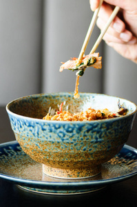 手持筷子的人手上放着一盘日式泰语中餐饭蘑菇蔬菜。咖啡厅, 餐厅。商务午餐。复制空间