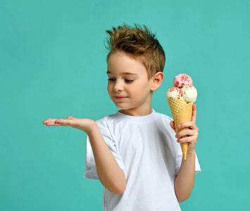 男孩孩子拿着草莓冰淇淋在华夫饼锥在蓝色薄荷背景