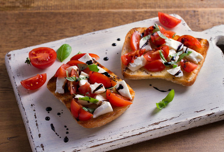 Caprese Bruschetta。西红柿, 罗勒, 芝士干酪和香醋在土司上减少小雨。开胃菜来菜