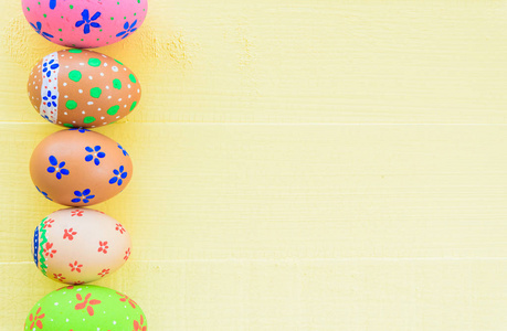 复活节快乐五颜六色的复活节彩蛋与五颜六色的纸花在明亮的黄色木质背景
