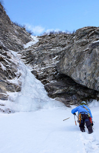 在阿尔卑斯的一个狭窄的冰冻 couloir 中, 雄冰登山者接近一个长而陡峭的瀑布。